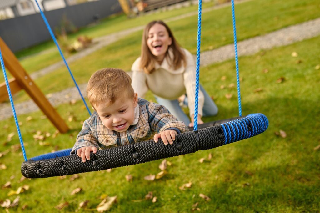 Woman pushing swing with joyful foster child